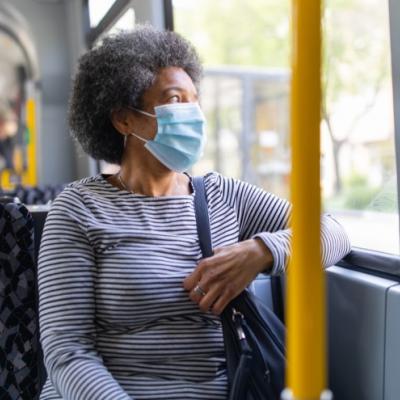 Senior woman on bus wearing mask.