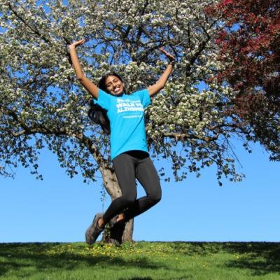 Young woman wearing a IG Wealth Management Walk for Alzheimer's shirt and jumping in joy in a park.