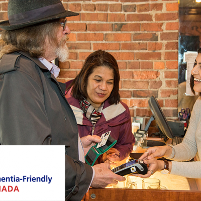 Two senior citizens having a pleasant conversation with a retail worker. The Dementia-Friendly Canada logo is visible in the lower left corner.