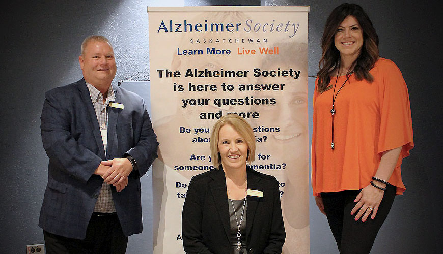 Our President, CEO, and Past President in front of an Alzheimer Society of Saskatchewan pop-up sign.