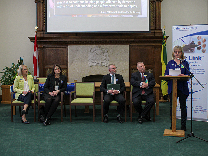 Elaine Unrau standing at a podium sharing her lived experiences with dementia.