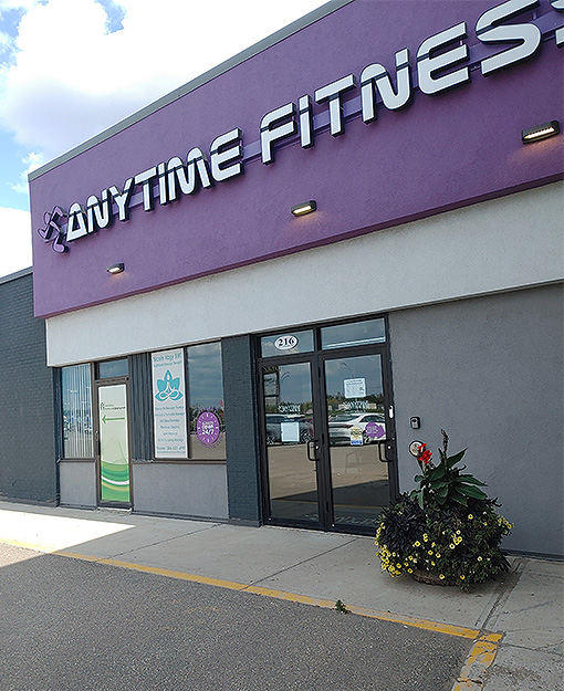 Anytime Fitness Yorkton's exterior. The bottom half of the building is grey and the top half is a bright purple with "Anytime Fitness" letters in silver.