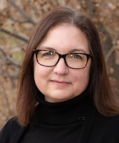 A headshot of Dr. Julie Kosteniuk. She has shoulder-length brown hair and is wearing glasses and a black turtle neck.