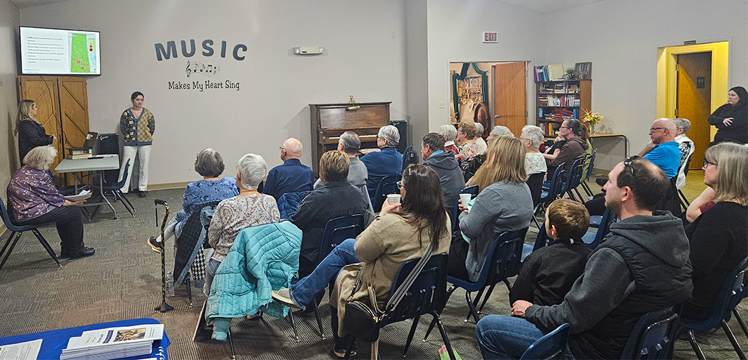 Three of our team members presenting to a group of attendees who are seated in chairs.