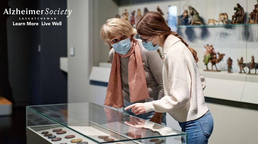 A museum guide explaining an exhibit to a senior citizen.