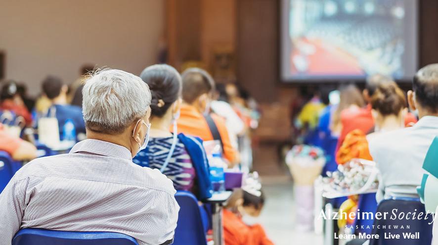 Community members watching a public presentation on a projector screen.