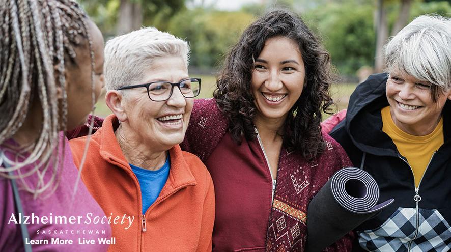 A group of women laughing together after an outdoor yoga class.