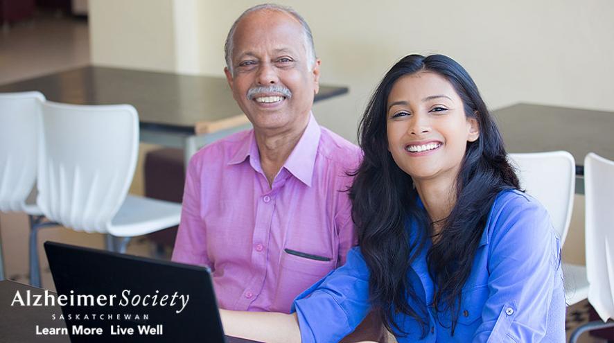 A father and daughter smiling as they complete an online questionnaire together.