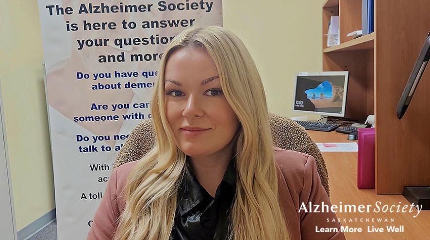 A photo of our summer practicum student in front of an Alzheimer Society banner.