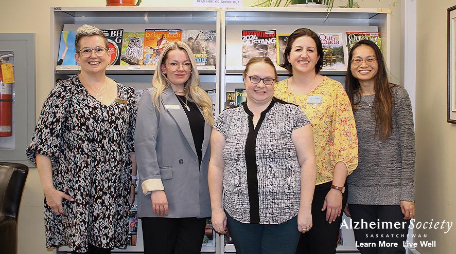 Alzheimer Society and Yorkton Public Library staff standing in front of a magazine rack.