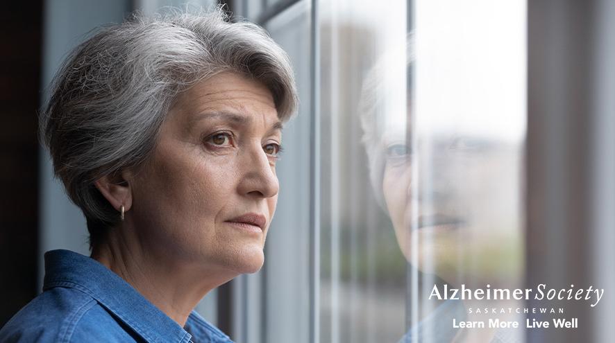 A woman who looks distressed is looking out a window.