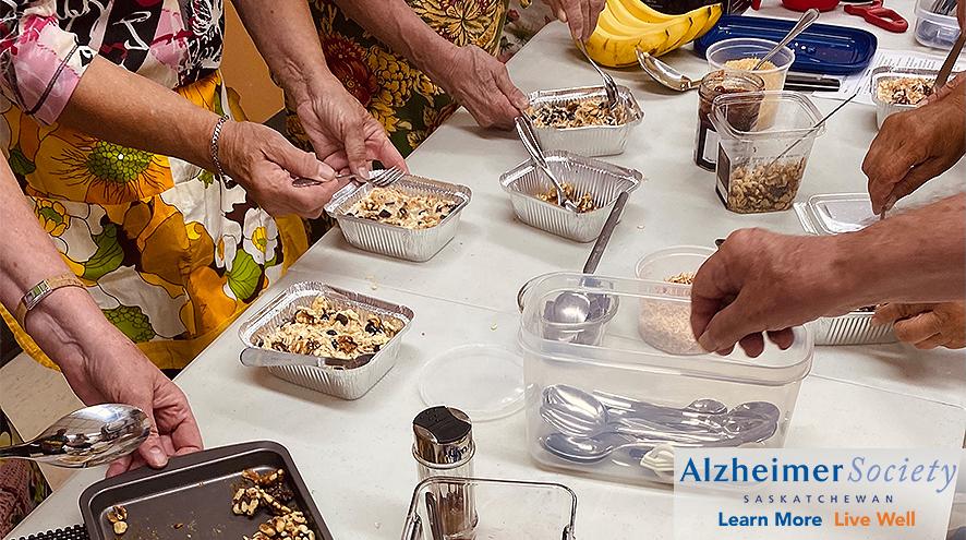 Multiple hands preparing individual pans of a dish with oatmeal and blueberries.