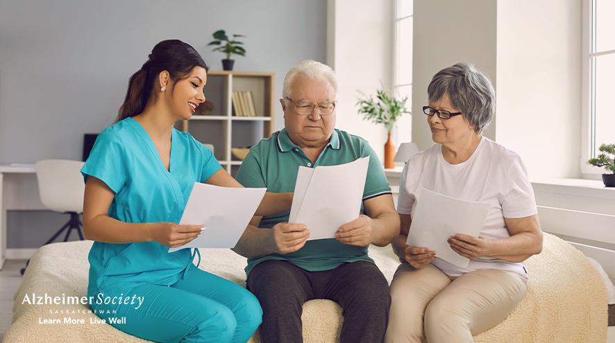 A health care professional sitting talking with a man and woman, who are smiling.