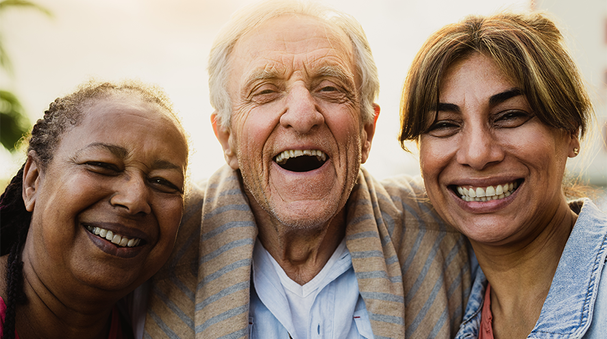 Image depicts 2 middle aged women and 1 older man smiling side by side