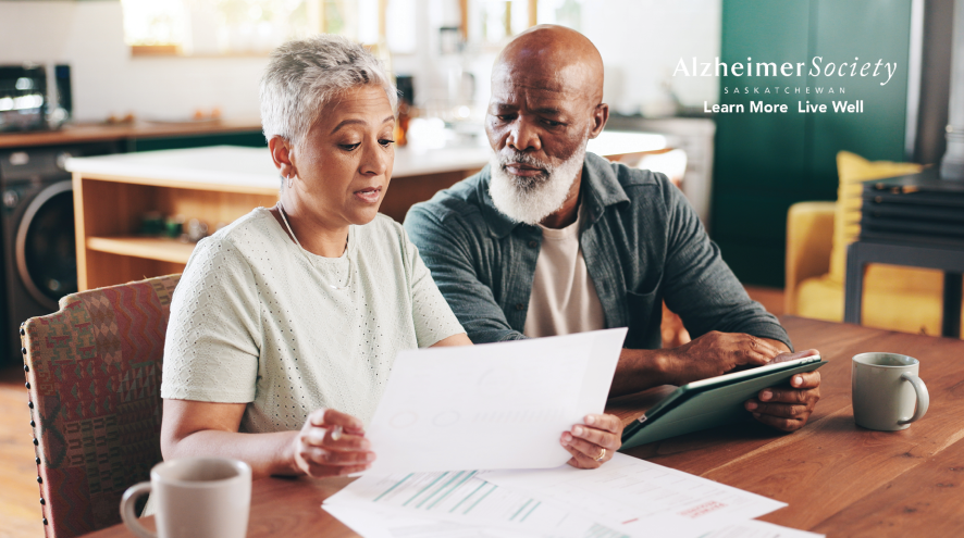 Image depicts two people sitting at a table looking at the same piece of paper.