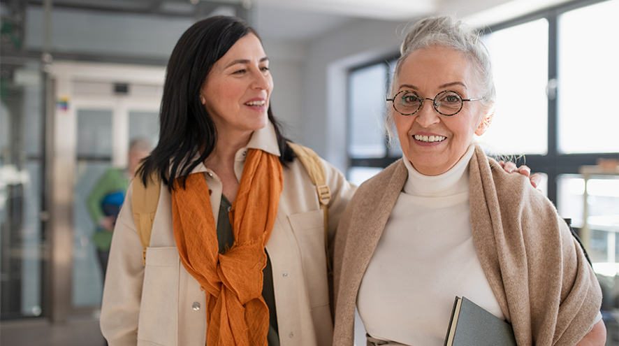 Image depicts one middle aged and one older woman smiling together