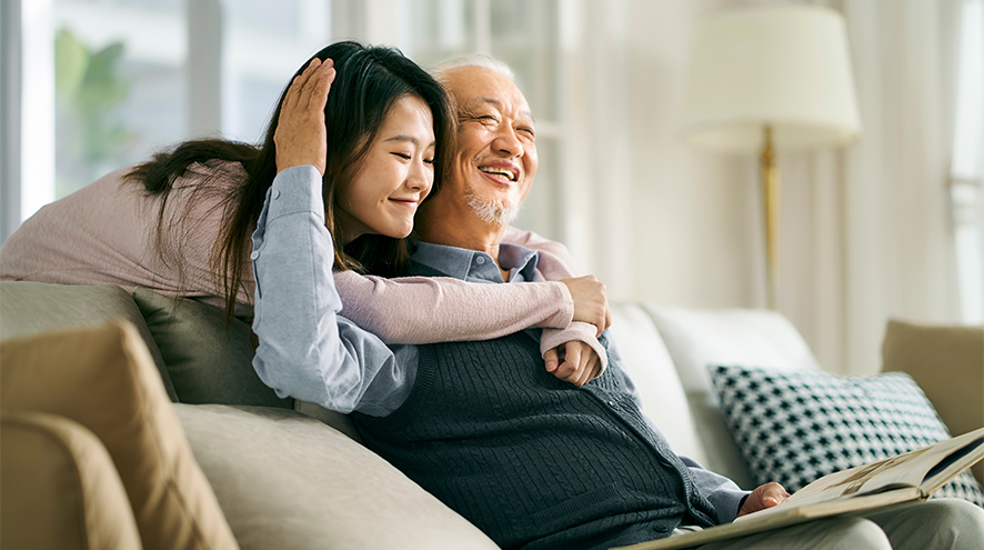 Image depicts younger woman giving and elderly man a hug