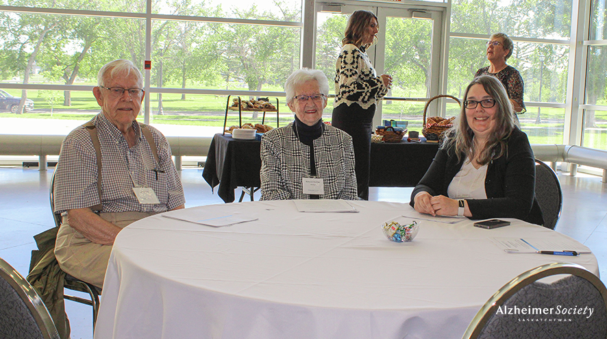 Three people sitting at a table smiling at our 2026 Annual General Meeting. They are in a bright room with a lot of natural light.
