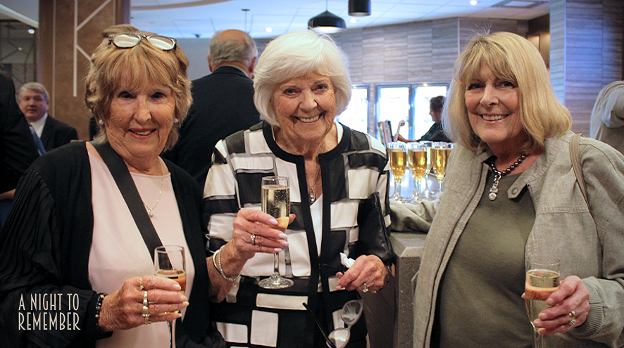 Three women posing together at our Night to Remember Gala. They are smiling during a toast.