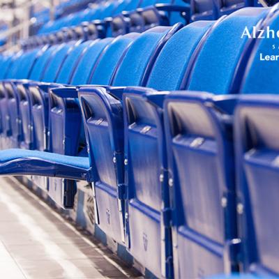 A row of folded arena seats with one seat flipped down in the middle of the row..
