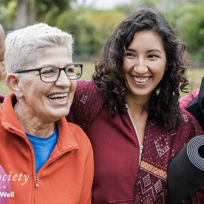 A group of women laughing together after an outdoor yoga class.