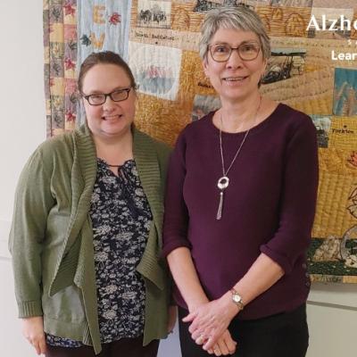 Our Dementia Community Coordinator standing in front of a patchwork quilt with Merle Willey 