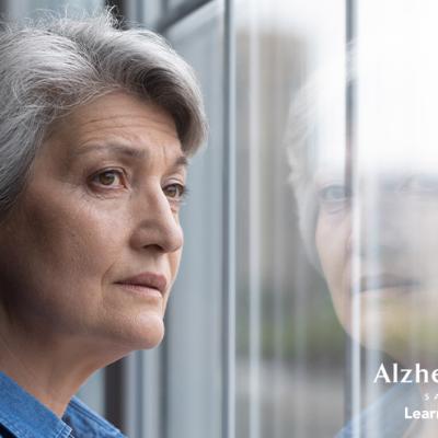 A woman who looks distressed is looking out a window. 