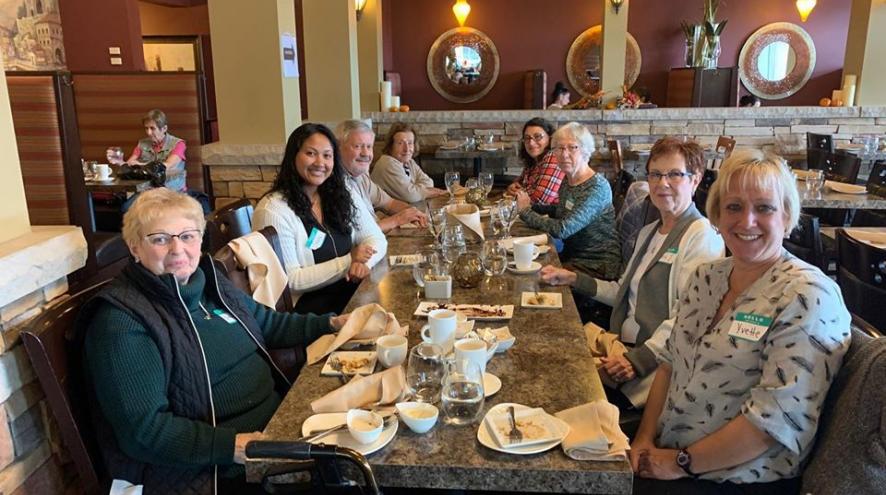 Group of people sitting at a dinner table in a restaurant smiling at the camera.