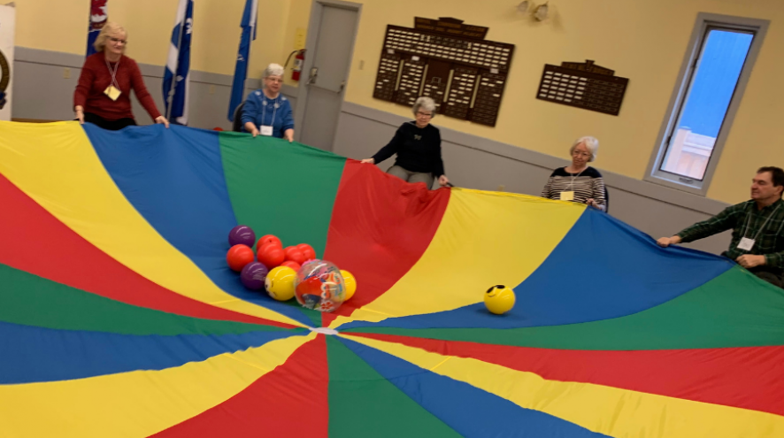 Group of people holding a parachute filled with balls