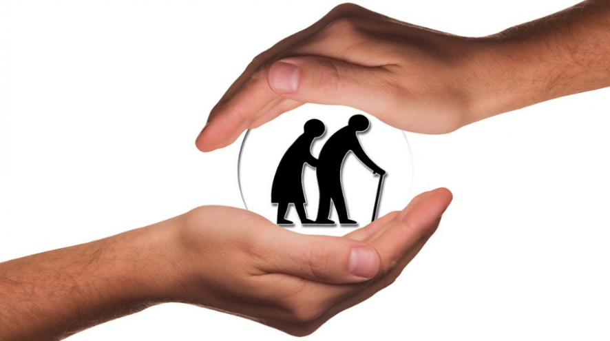 Image of hands holding the silhouette of an older couple in a glass ball.