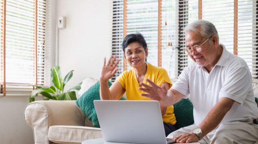 Older couple waves hello to a laptop screen 