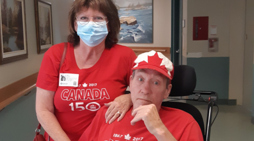 Woman with dark shoulder-length hair wearing a Canada 150 shirt resting on a man in a wheelchair wearing the same shirt