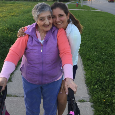 Gioulizar Smoian, who lives with dementia, standing with her walker and her granddaughter Selena Costabile hugging on a sidewalk